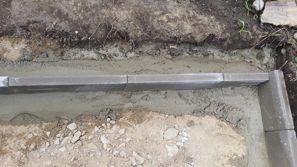 Här har vi lagt betong för att fixera kantstenen så att den inte flyttar på sig när vi vibrerar bärlagret för plattsättningen.